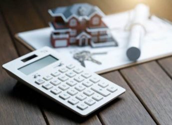 a calculator in front of a Villa house model with a blueprint